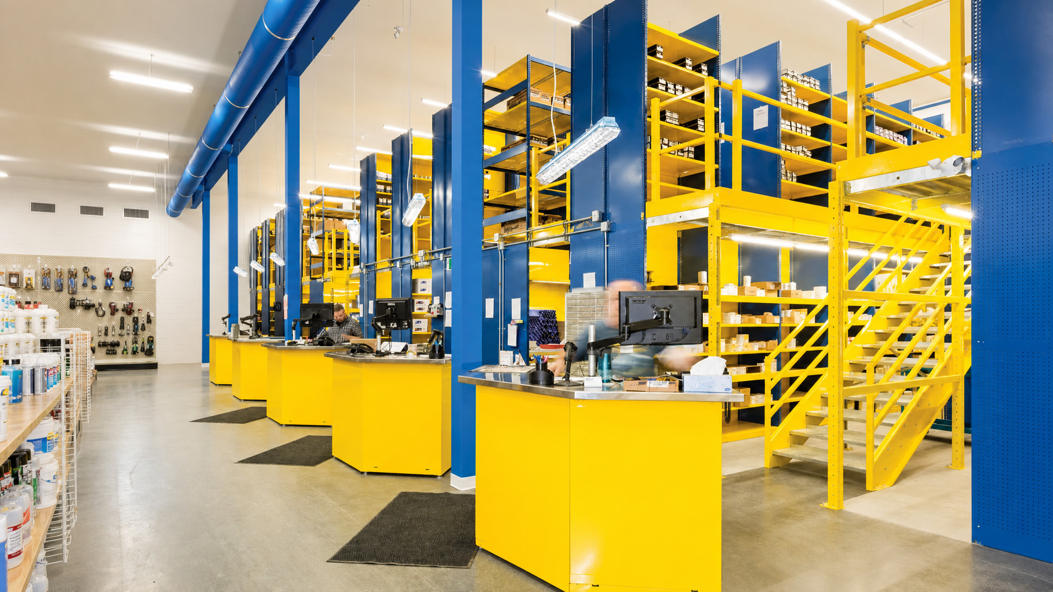 Multi-level blue and yellow racking system with integrated stairs and handrails.