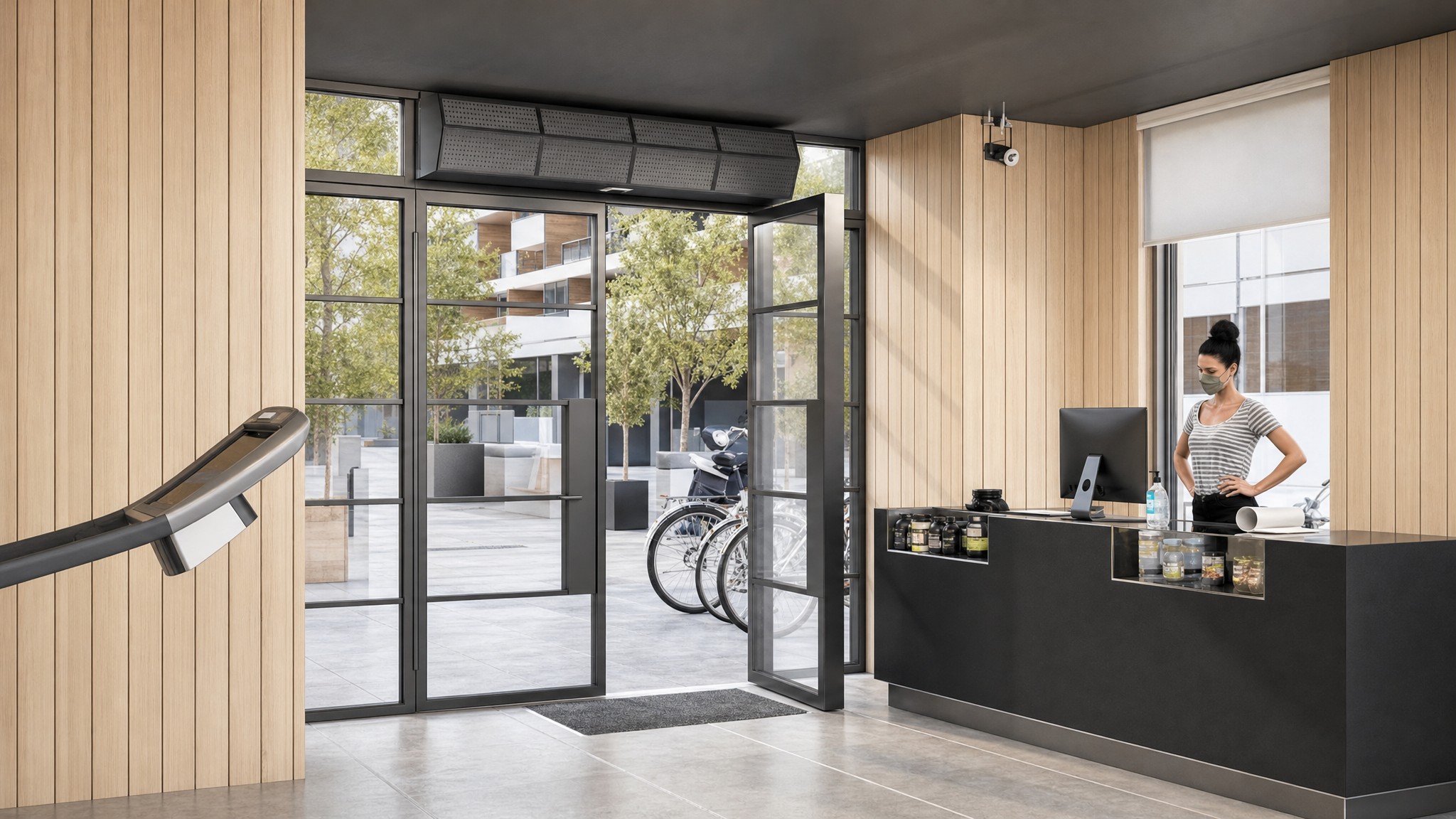 Glass double door with overhead air curtain in a modern room with wood panel walls.