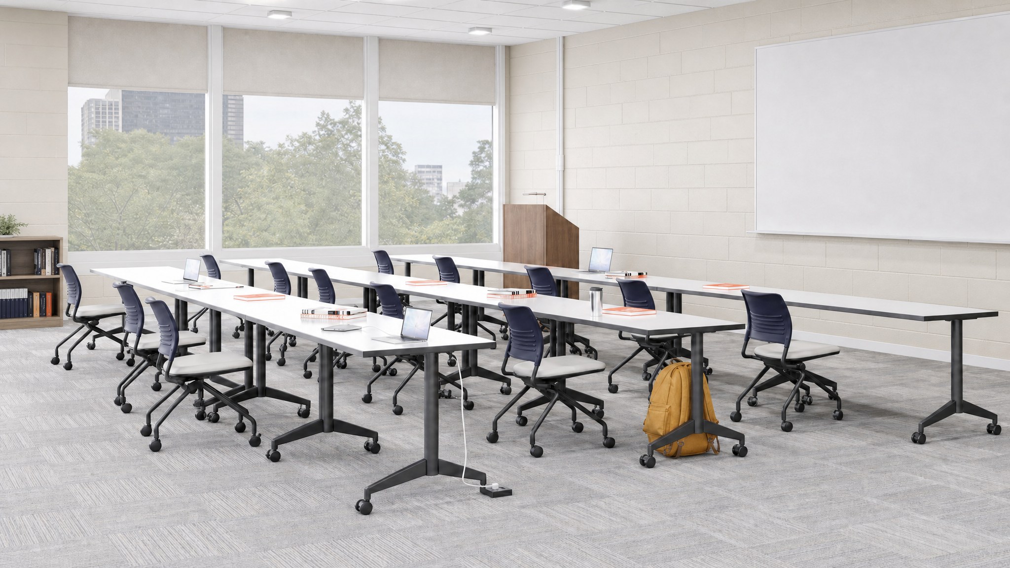 Black floor cable raceway on carpet between tables and rolling chairs in a classroom.
