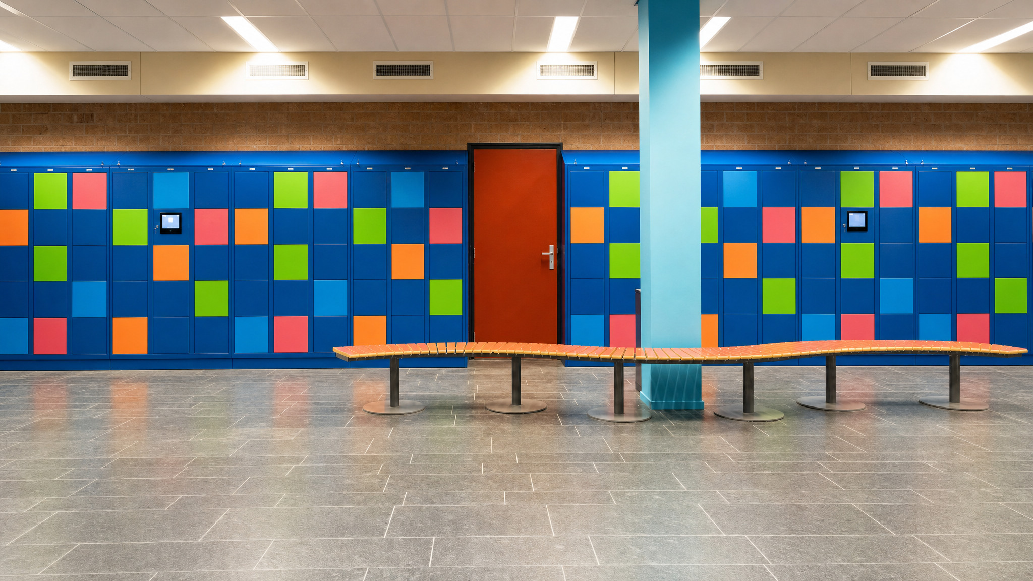 Wall of blue lockers with orange, green, and pink square doors in a spacious room.