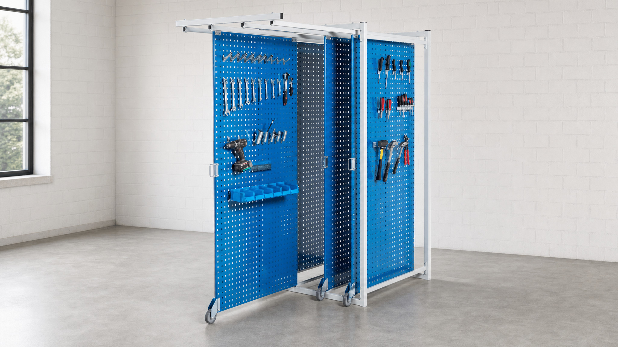 Blue sliding pegboard racks on wheels with mounted tools and bins in an empty room.